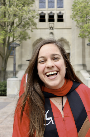 Headshot of Michelle Eastman, smiling at the camera with a red gown and black stole that has the universal handicap symbol on it.